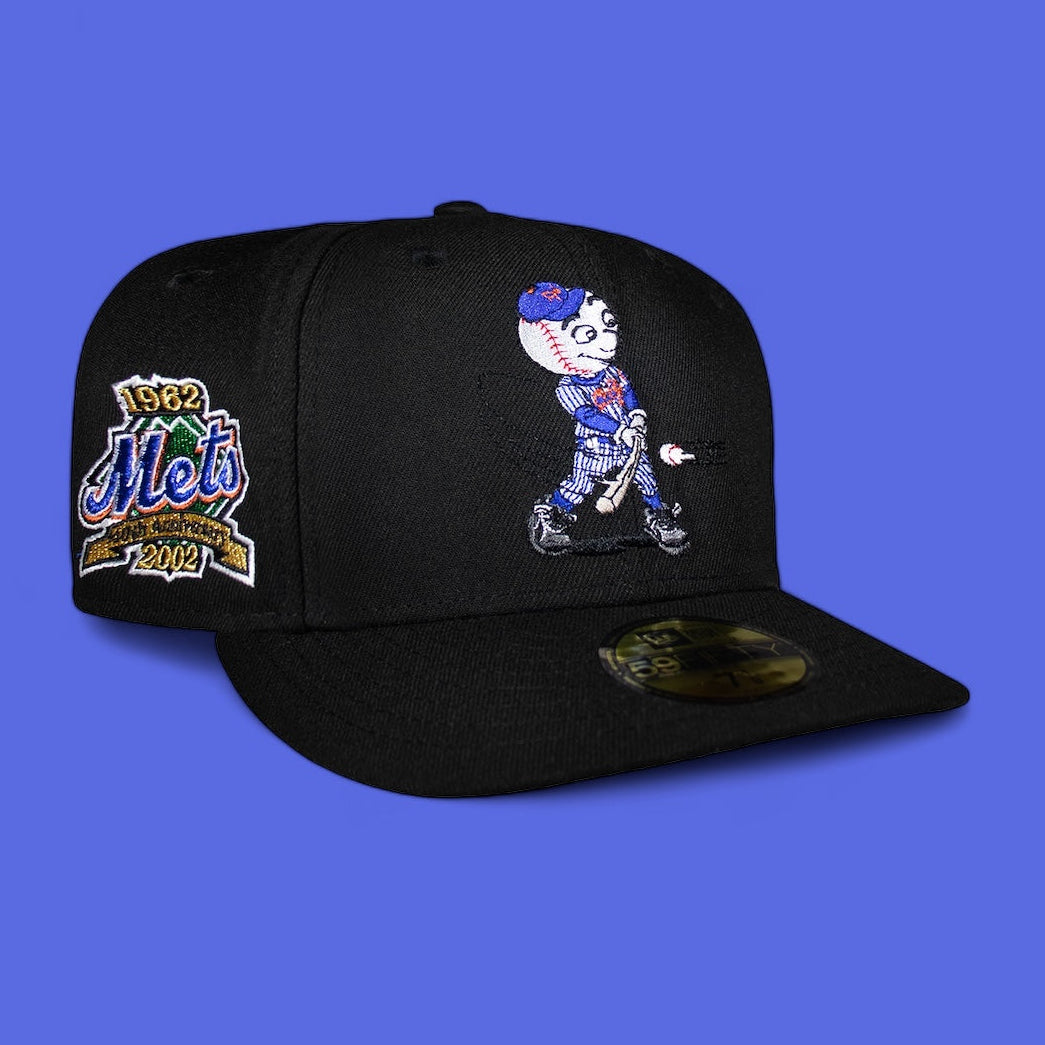 A black fitted cap with New York Mets branding and an illustrated character on the front.