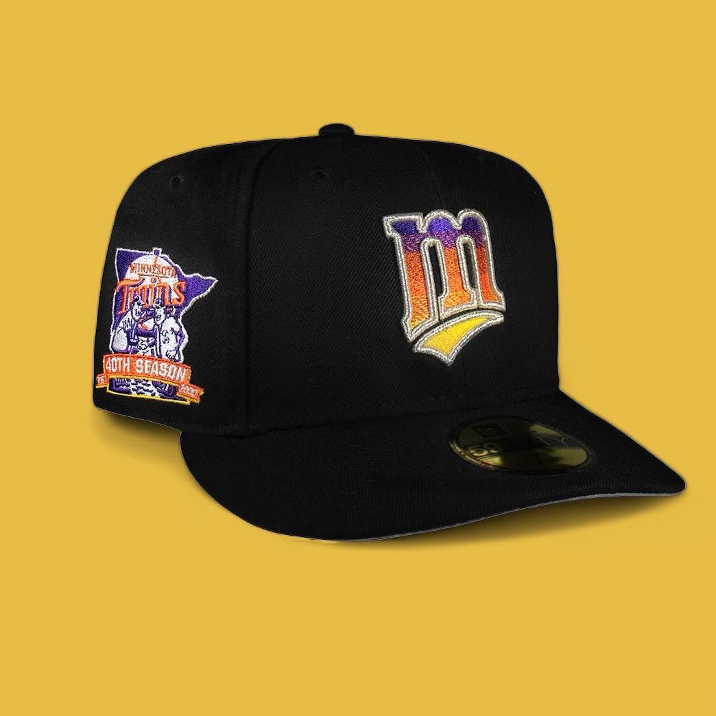 A black fitted baseball cap with the Minnesota Twins all black gradient logo and the number 40 on the side, set against a yellow background.